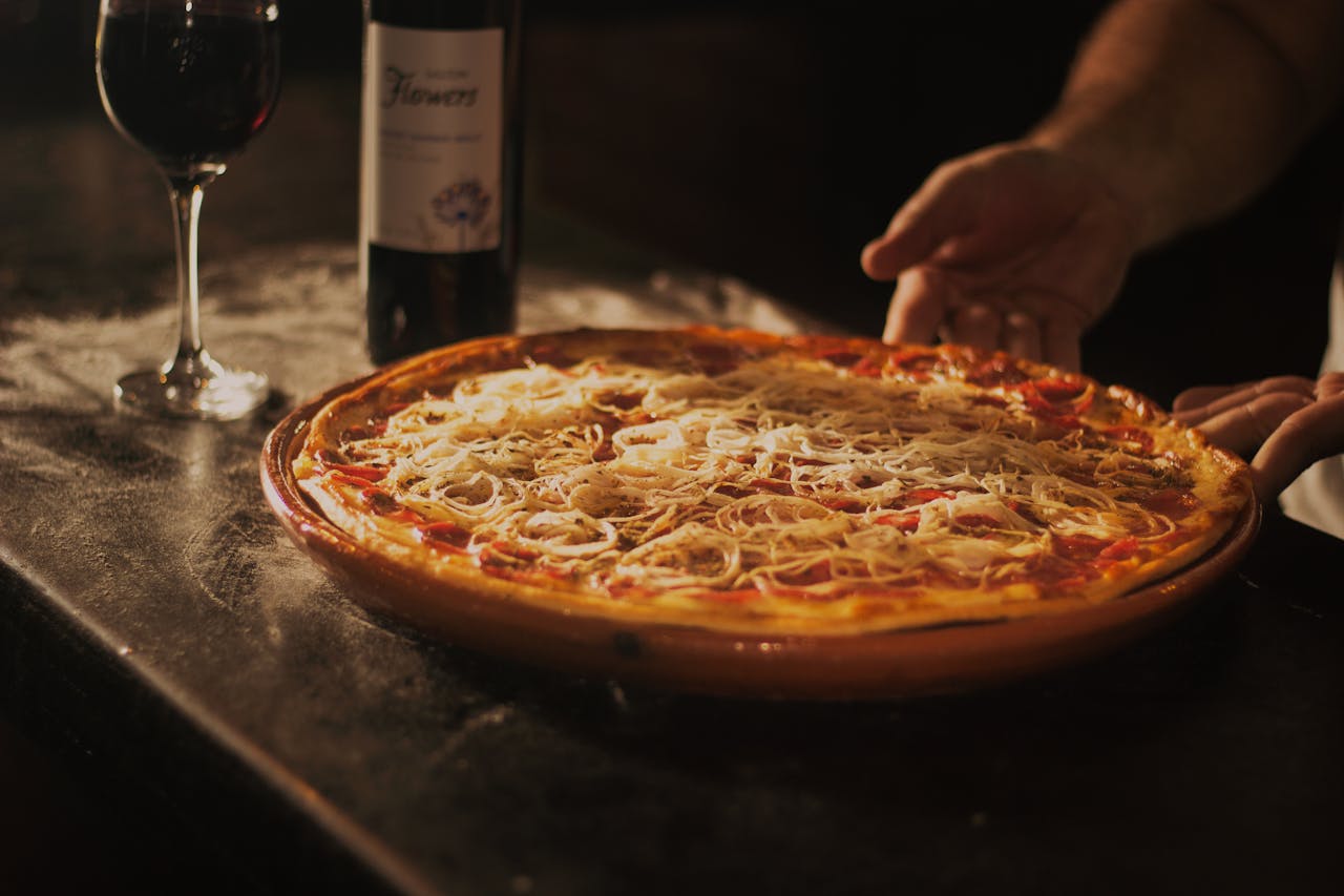 Delicious pepperoni pizza paired with red wine, showcasing a rustic dining experience in Centro, RJ.